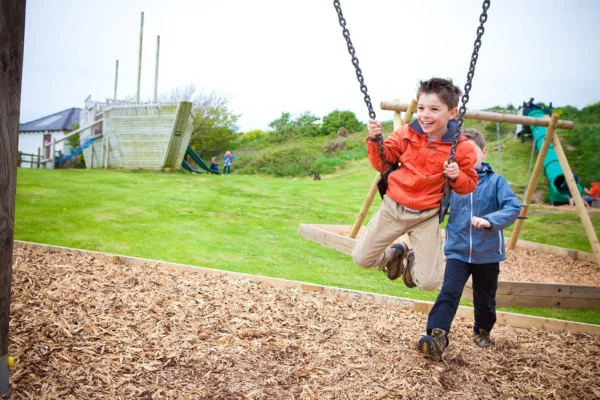 Children playing on the swings in the play area at Silver Bay