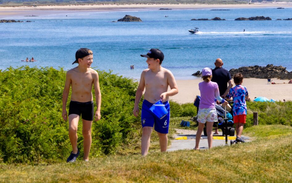A family walking the coast path down to the beach at Silver Bay
