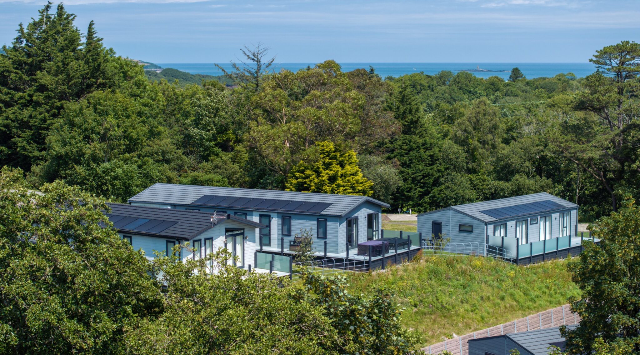 Lodges in the trees at Woodland Falls, with the sea beyond